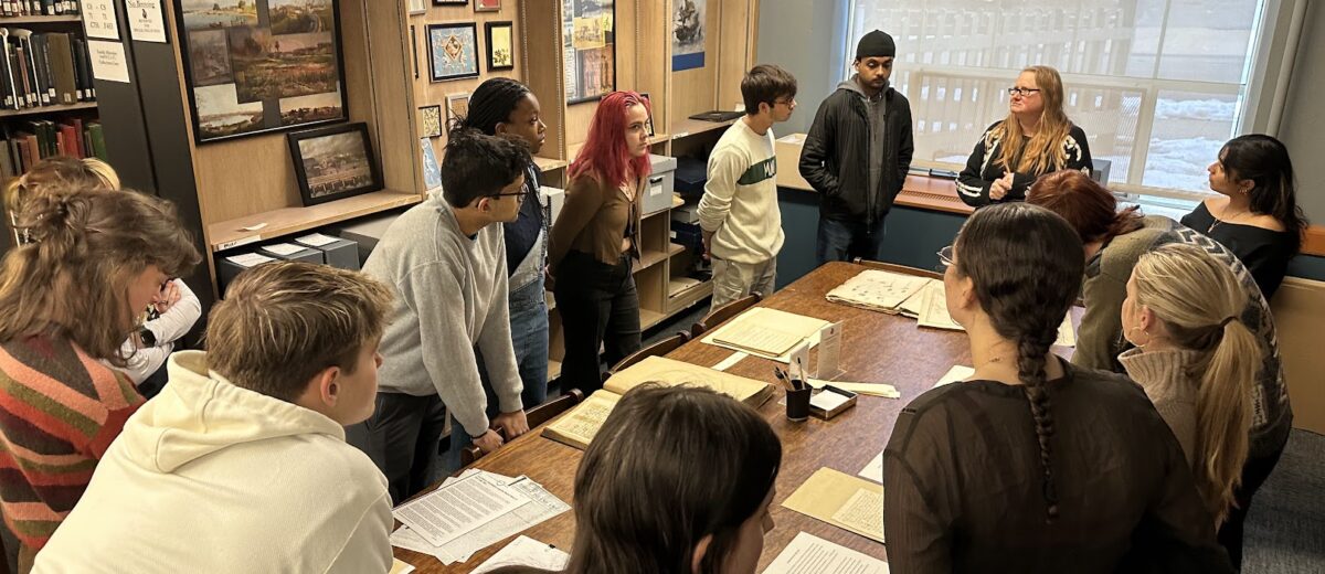 Students looking at documents around a table.